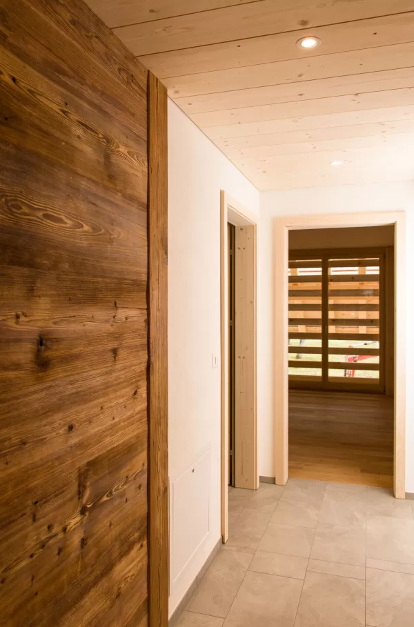 Flur mit heller Holzdecke und Kombination aus hellen und dunklen Holzelementen. Der warme Kontrast zwischen naturbelassenem und geöltem Holz verleiht dem Innenraum eine moderne und zugleich gemütliche Atmosphäre