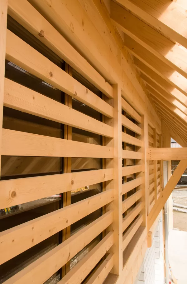 Detailaufnahme einer modernen Holzfassade mit horizontalen Lamellen. Die präzise ausgeführte Zimmermannsarbeit zeigt gleichmäßige Linienführung und hochwertige Verarbeitung des hellen Fichtenholzes.